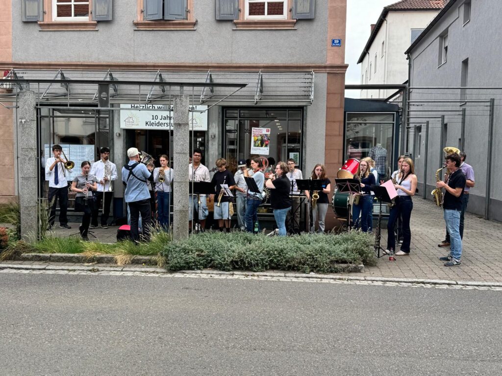 Die United Concert Band spielt vor einem Geschäft an der Hauptstraße in Herxheim.