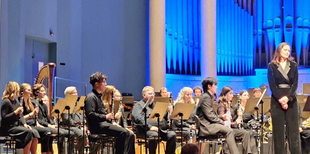 Das Symphonic Wind Orchestra Mannheim auf der Bühne des Musensaals vor der blau beleuchteten Orgel